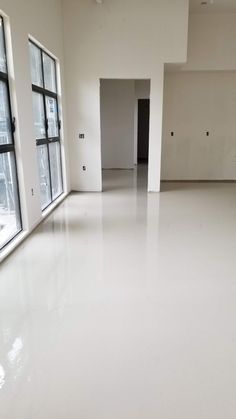 an empty room with white floors and windows