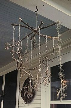 a wind chime hanging from the side of a house with branches and twigs attached to it