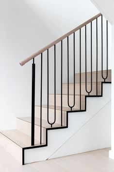 a staircase with black railing and wooden handrails in a white house or apartment