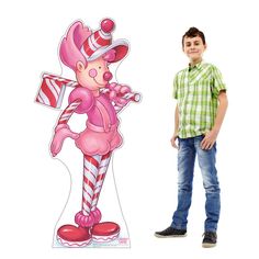 a young boy standing next to a cardboard cutout of a cartoon character with candy canes