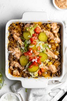 a casserole dish filled with meat, vegetables and dressing on a white surface