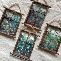 four old window frames are hanging on a white sheet with twine rope and flowers painted on them