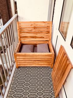 a wooden bench sitting on top of a balcony next to a door with pillows in it