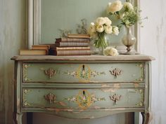 an old dresser with flowers and books on it