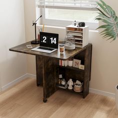 a wooden desk with a laptop on it in front of a window and a potted plant