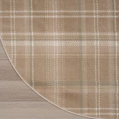 a beige and white plaid area rug on top of a wooden floor with an oval border