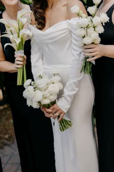 three bridesmaids in black and white gowns holding bouquets with flowers on them