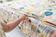 a close up of a baby's hand reaching for a pillow on top of a bed