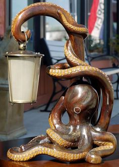 an octopus lamp sitting on top of a wooden table next to a light post and bench