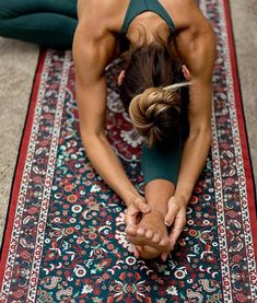 a woman is doing yoga on a rug with her hands together in the shape of a heart