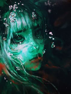 a woman with green hair and makeup in the water looking into the camera while she is surrounded by bubbles