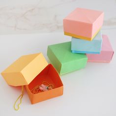 four different colored boxes sitting next to each other on top of a white table with a gold chain