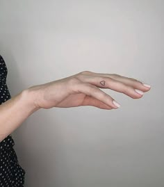 a woman's hand with a tiny heart tattoo on it