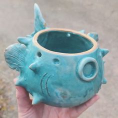 a hand holding a blue ceramic fish vase