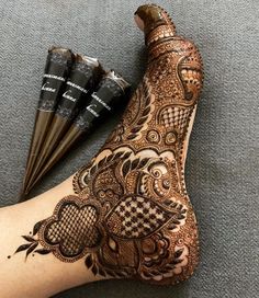 henna tattoo on the foot with three brushes next to it and two cones in front