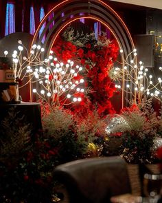 a room filled with lots of red flowers and lights on the wall next to it