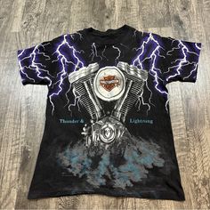 a black t - shirt with an image of a motorcycle engine on it and lightning in the background