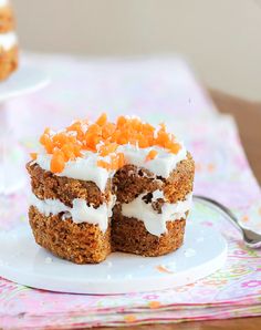 two cupcakes with frosting and orange zest on top are cut in half