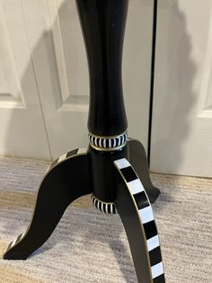 a black and white table with a striped ribbon around it's legs on carpeted floor