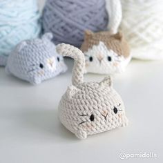 three crocheted cats sitting next to each other on top of a white table