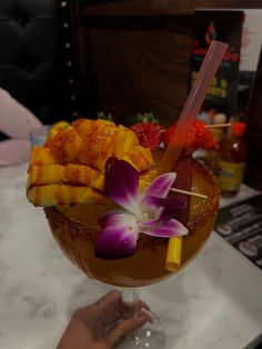 a person holding a drink with fruit on the rim