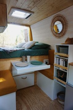 a small room with a bed, desk and shelves on the wall next to it