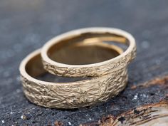 two gold wedding bands sitting on top of each other