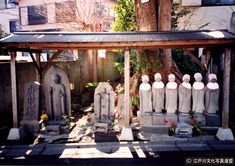 a group of statues sitting in front of a building next to a tree and fence