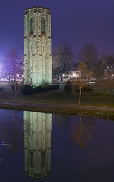 a tall tower with a clock on it's side next to a body of water