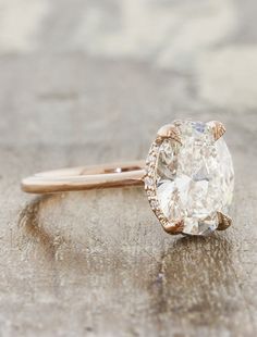 a close up of a diamond ring on a wooden surface