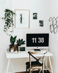 a white desk topped with a computer monitor next to a green plant and potted plants