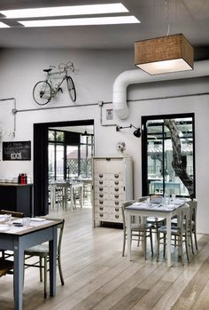 an empty room with tables, chairs and bicycles hanging from the ceiling