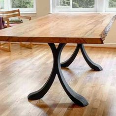 a wooden table sitting on top of a hard wood floor next to two chairs and a window