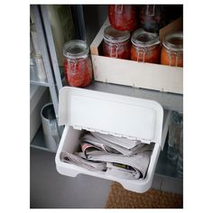 an open refrigerator filled with lots of jars and paper on top of it's shelves