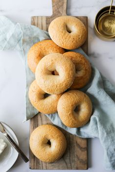 doughnuts sitting on top of a cutting board next to a bowl of cream cheese