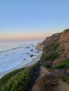 the beach is next to some cliffs and water