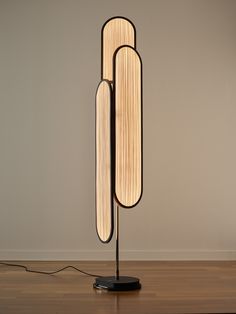 a lamp that is on top of a wooden floor in front of a white wall