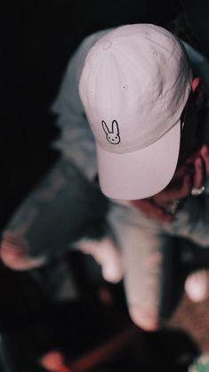 a person wearing a white hat with a bunny ear on it's side and one hand in the air