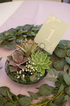 succulents and greenery are arranged on a table with a number one sign