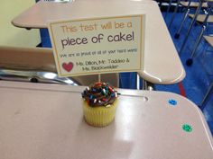 a cupcake with sprinkles sitting on top of a table next to a sign that says, this test will be a piece of cake