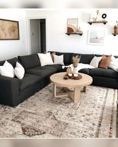 a living room filled with black couches and white pillows on top of a rug