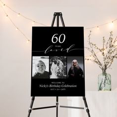 a black and white 60th birthday card on a easel with lights in the background