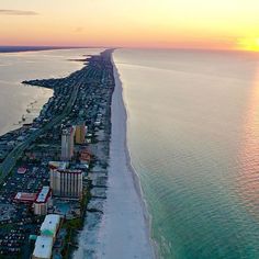 an aerial view of the beach and ocean at sunset