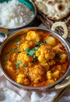 a bowl filled with curry and cauliflower next to rice