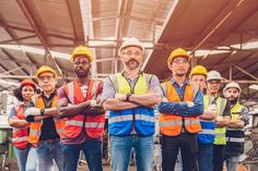 a group of construction workers standing together in front of a building with their arms crossed