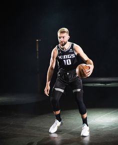 a man holding a basketball on top of a court in front of a black background