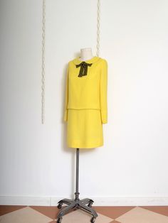 Vintage 60s, vibrant yellow drop waist dress by Carlette, with a choir-boy collar, attached black polka dot neck tie, chest yoke detail, long slim fit sleeves with fixed buttons on a gauntlet cuff, fold-over drop waist detail, lined bodice, zipper back closure. Union made in USA Fits Like * Small // Vintage Label Size * 11 Measurements * 38" bust // 34" waist // 37" hips // 15" shoulders // 22" sleeve // 33" length   Circa * between 1964 - 1973 Fabric * best guess is a Cotton/Rayon blend Condition * Good overall / some dinginess throughout, see photos (sleeve cuffs, along tops of collar and shoulder), subtle armpit discoloration Please message with any questions Vintage items are a minimum of 20 years old and may show signs of age. We do our best to describe and photograph any noticeable i 1960 Outfits 60s Style Retro, Wardrobe Corner, Armpit Discoloration, Mod Style 60's, Vintage 60s Dress, Mod Dress 60s, Gamine Style, Vintage Dress 60s, Photo Sleeve