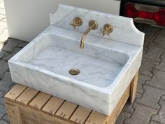 a white marble sink sitting on top of a wooden bench