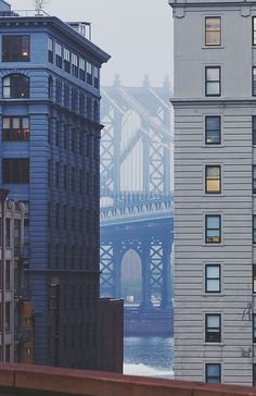 an image of a bridge in the distance with buildings on either side and water below