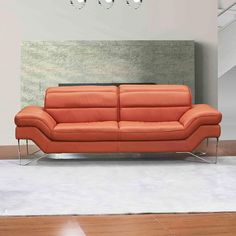 an orange leather couch sitting in front of a wall with chandelier above it